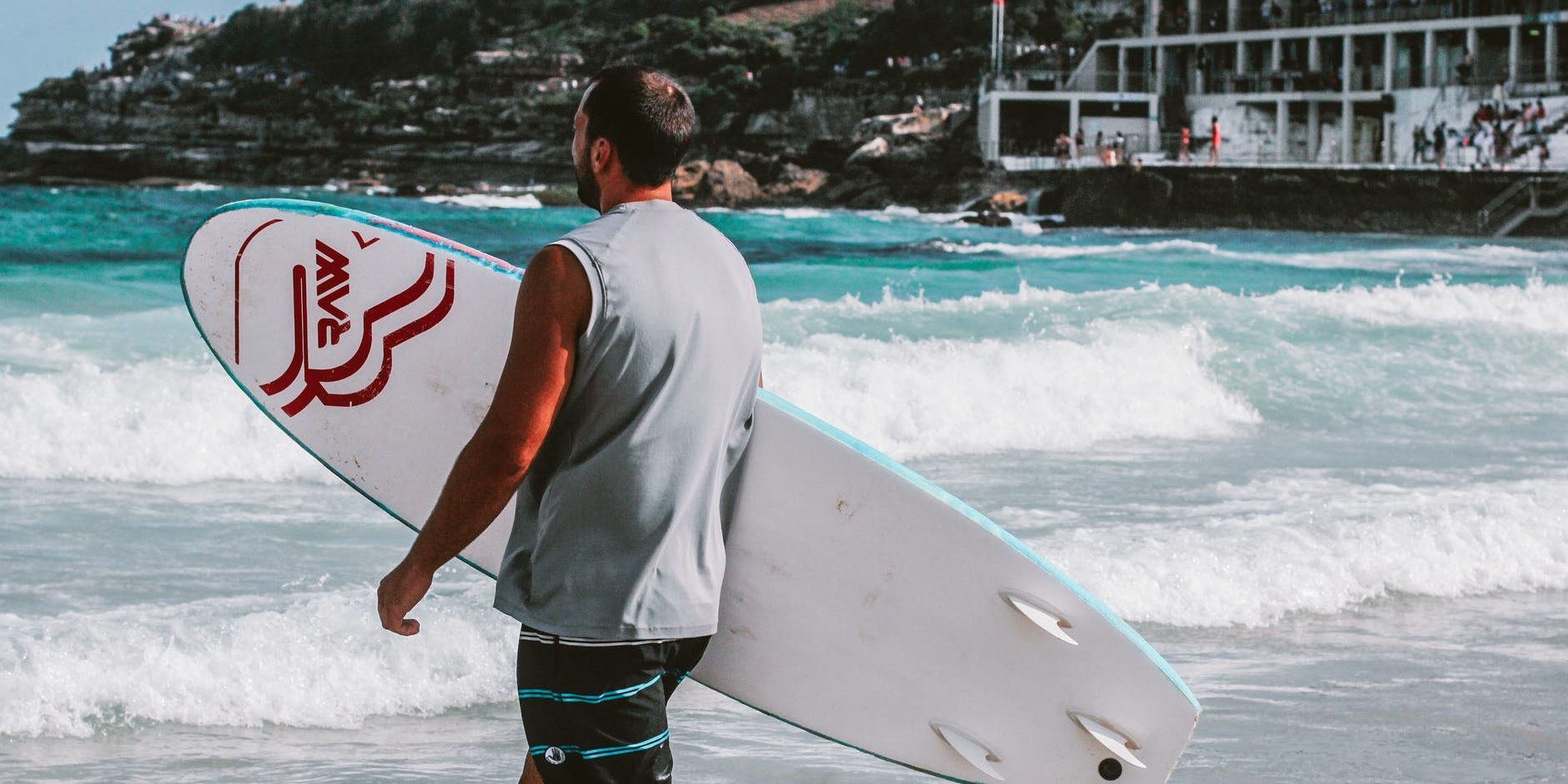 pexels-photo-785133 man walking towards body of water holding a surfboard
