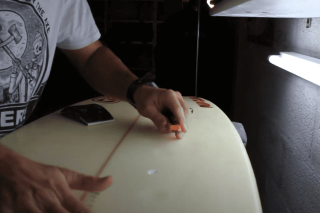 reparation d'un pet sur la carène d'une planche de surf