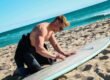 surfeur en train de waxer sa planche de surf