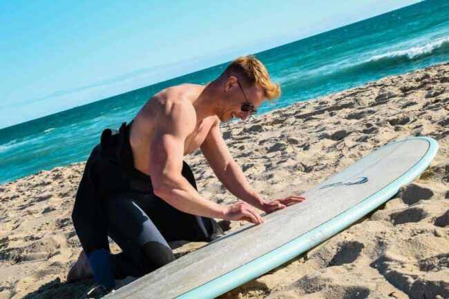 waxer sa planche de surf surfeur en train de waxer sa planche de surf